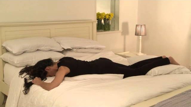 Still from Sleep Positions, showing a sleeping position demonstrated on a bed